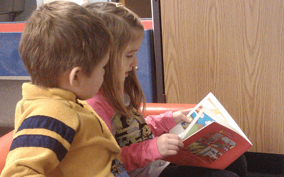 School District 4k Partnership image, shows two children reading a book together.